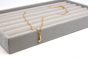 Nahaufnahme einer goldenen Edelstahlkette mit einem polierten Buchstaben J Anhänger