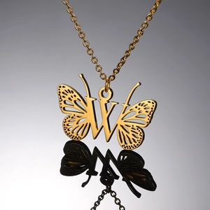 Detailopname van de gouden vlinderketting met letter W op een donker reflecterend vlak