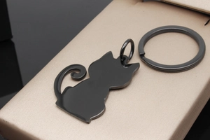 Macro view of black cat-shaped stainless steel pet ID tag with split ring on gold pad