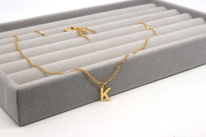 Detailansicht der goldenen Halskette mit K-Anhänger auf einem Samt-Schmuckdisplay