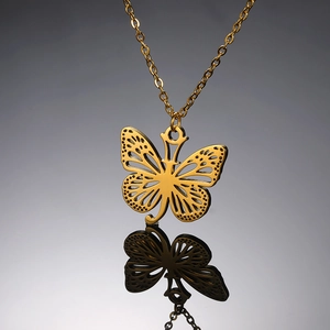 Macro detail van gouden vlinderhanger met verfijnde patronen en een fijne gouden schakelketting