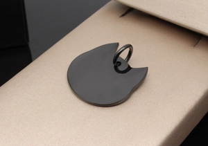 Cat head shaped black metal pet tag with a polished mirror finish on a display box