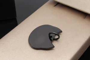 Close-up of polished black moon-shaped pet ID tag on a champagne silk display box