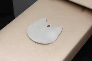 Polished cat-shaped stainless steel pet ID tag shown on a premium gift box surface