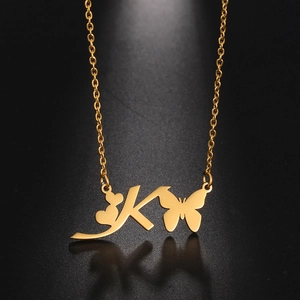Detail of gold butterfly and heart pendant with letter K on stainless steel necklace