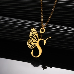 Detail macro-opname van een gouden vlindervleugel hanger met de letter S aan een ketting