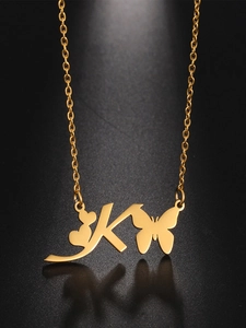 Macro detail of gold stainless steel necklace featuring letter K butterfly and heart
