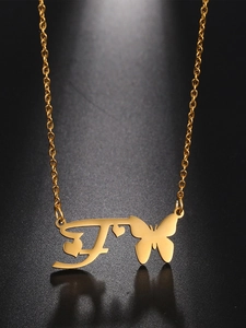 Detailed close-up of golden butterfly, heart and letter F pendant on a necklace