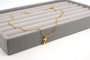 Detailaufnahme der goldenen Buchstabe Z Kette auf einem grauen Samt Schmuckdisplay