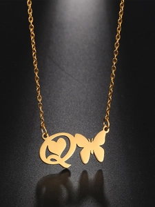 Macro shot of gold butterfly and letter Q heart pendant necklace on dark background