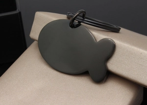 Detail of fish-shaped black stainless steel pet tag on champagne satin gift box