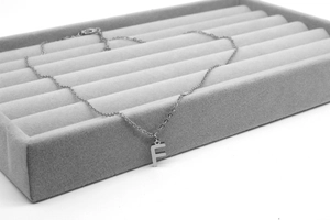 Makro-Detail der silbernen Edelstahl Halskette mit Buchstaben-F auf Samttablett
