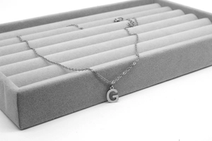 Detailaufnahme des Buchstaben-G-Anhängers an feiner Edelstahlkette auf Samtunterlage