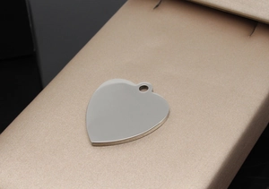 Close-up of polished heart-shaped stainless steel pet ID tag on elegant champagne silk background