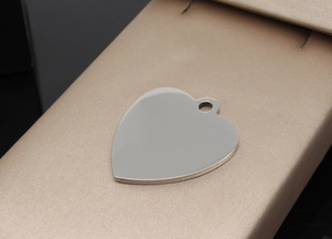 Detailed macro view of heart-shaped stainless steel pet ID tag on elegant silk