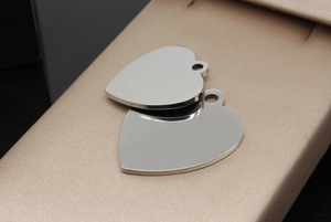 Polished heart-shaped stainless steel pet tags with mirror finish on a jewelry box