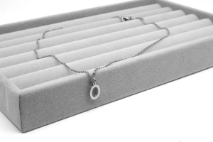Detail der silbernen Kette mit O-Anhänger in einer Schmuckschale präsentiert