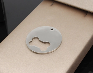 Close-up of a silver stainless steel dog tag with a hollow bone cutout on a brushed surface