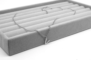 Detailansicht der silbernen Kette mit Buchstaben-V-Anhänger in einem Schmucktablett
