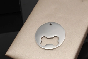 Polished stainless steel round pet ID tag with bone cutout detail on a silk stand