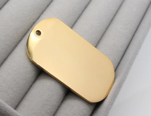 Close-up of polished gold rectangular stainless steel pet tag on grey velvet display
