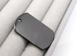 Macro shot of polished black stainless steel pet tag with mirror finish and pre-drilled hole