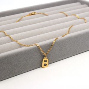 Goldene Edelstahl Halskette mit Buchstaben B Anhänger auf grauem Samt Schmucktablett