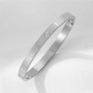 Détail macro de la gravure JESUS et des icônes religieuses sur le bracelet en acier argent