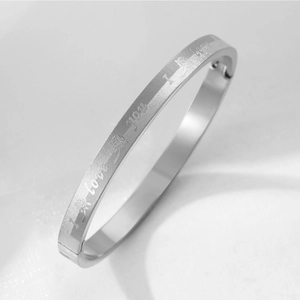 Detailed close-up of engraved I LOVE YOU quote and rose on steel bangle with brushed finish