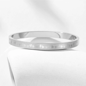 Macro shot of a silver titanium steel heart pattern bangle with a matte finish and hinge