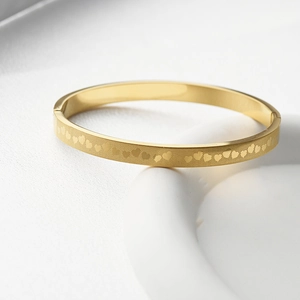 Macro detail of golden stainless steel bangle featuring etched heart grid pattern
