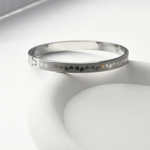 Macro detail of silver stainless steel bangle with engraved heart pattern on stone stand