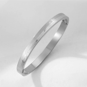 Detail of silver stainless steel bangle featuring rose engraving and Forever script