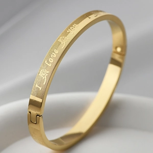 Close-up of golden stainless steel bracelet featuring I Love You engraving and floral pattern
