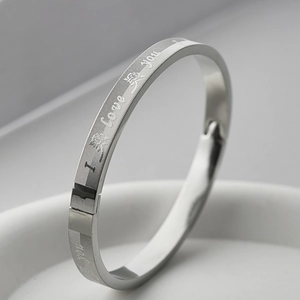 Close-up of silver stainless steel bangle with engraved I Love You text and rose patterns