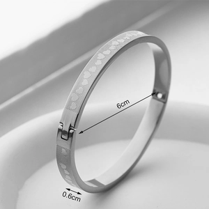 Detail view of steel bangle showing 6cm diameter and 0.6cm width with heart patterns