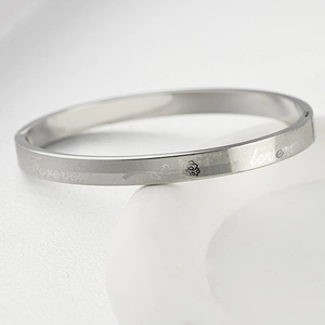 Macro detail of silver stainless steel bangle with Forever Love and rose engraving