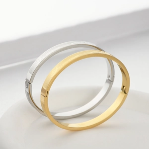 Detail shot of gold and silver steel bangles with forever engraving and brushed texture
