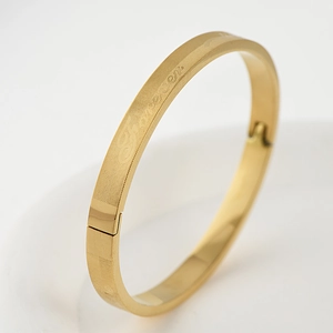 Macro detail of gold stainless steel bangle featuring Forever engraving and textured finish
