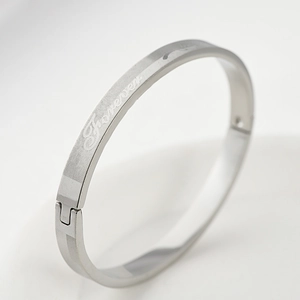 Detail view of silver stainless steel bangle with engraved strength text and mesh texture