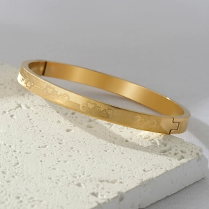 Gold titanium steel bracelet with engraved interlocking pattern on white stone base