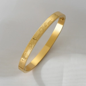 Gold titanium steel hinge bracelet with brushed texture and engraved heart pattern motifs