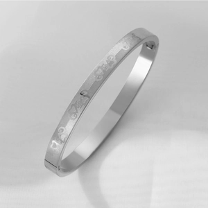 Detail shot of silver stainless steel bangle featuring etched heart grid and clasp