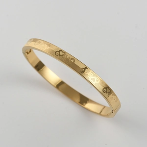 Detail of gold matte titanium steel bangle featuring heart and mesh pattern engraving