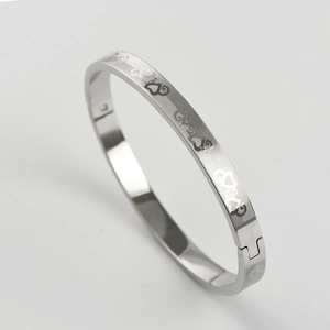 Close-up of silver stainless steel bangle with cat and heart engraved patterns