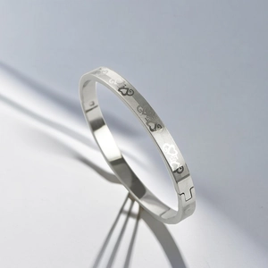 Macro detail of silver stainless steel bangle with engraved heart pattern and clasp
