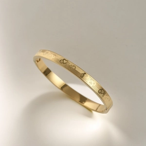Close-up of gold titanium steel bangle showing love heart grid and side clasp