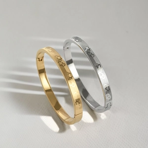 Detail of gold and silver steel bangles with engraved heart patterns and buckle closure