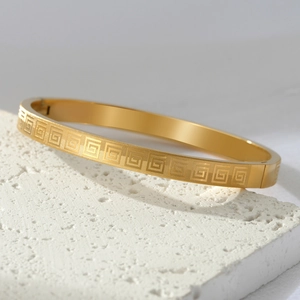 Polished gold titanium steel bangle featuring a classic Greek key pattern and hinge clasp