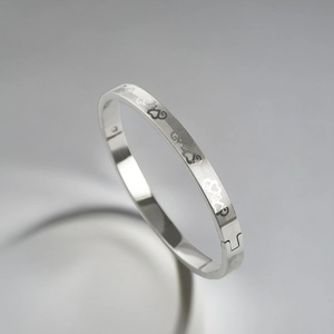 Detail shot of silver stainless steel bangle with engraved heart grid and buckle